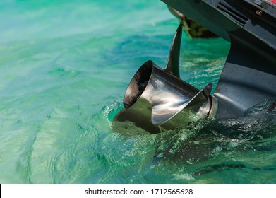 Close up stainless steel motor boat propeller on turquoise sea water background.