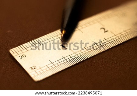 Close up of a stainless steel scale r ruler showing a one inch point with pen, Selective focus, isolated on Dark
