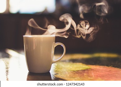 Close up of steaming cup of coffee or tea on vintage table - early morning breakfast on rustic background - Powered by Shutterstock