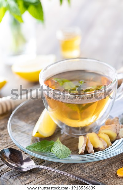 Close up of steaming hot green tea with mint,\
lemon and ginger.