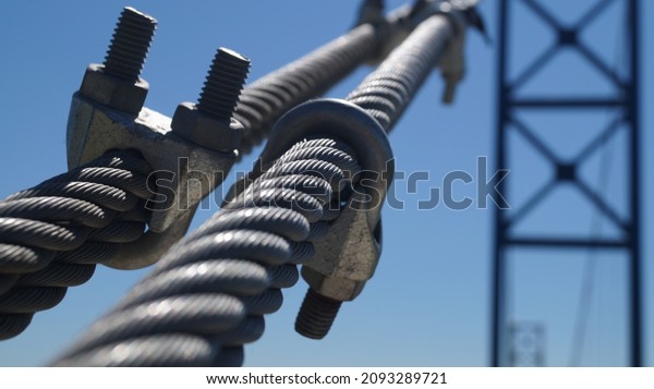 close up of a steel cable fixed by\
steel threaded clamps holding a suspension\
bridge