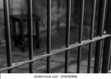 Close up of steel cage of jail and blurry chair background