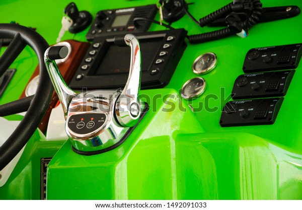 close up of a steering wheel and  a throttle control\
lever on a speed boat