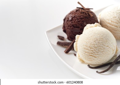 Close Up Still Life of Scoops of Vanilla and Chocolate Ice Cream with Chocolate Shavings and Vanilla Beans on White Platter in front of White Background with Copy Space