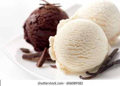 Close Up Still Life of Scoops of Vanilla and Chocolate Ice Cream with Chocolate Shavings and Vanilla Beans on White Platter in front of White Background