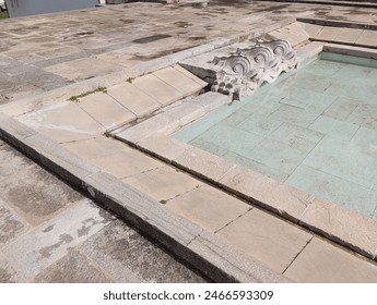 Close up of a stone pool filled with water adorned with the sculpted fish heads of dolphins. Lisbon, Portugal - Powered by Shutterstock