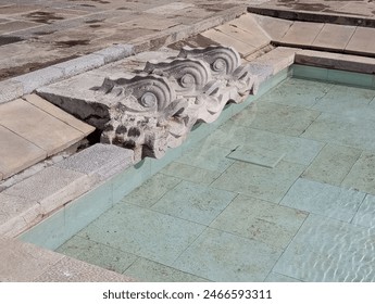 Close up of a stone pool filled with water adorned with the sculpted fish heads of dolphins. Lisbon, Portugal - Powered by Shutterstock