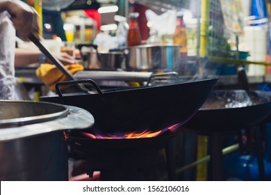 Close Up Of Street Food Stall Cooking Fresh Asian Stir-fry Dinner In Wok With Flames - Local Chef Preparing Meal Orders At Outdoor Night Market - Thai Cuisine, Culture And Travel Concept