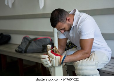 Close up of stressed cricket player sitting on bench at locker room - Powered by Shutterstock