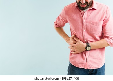 Close up of a stressed man in his 30s suffering from a gallbladder sickness. Latin man in a lot of pain due to gallstones next to copy space - Shutterstock ID 1996274408