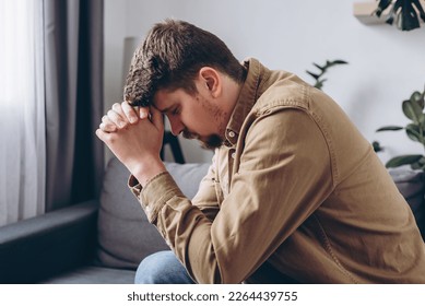 Close up of stressful sad young man sitting alone on sofa in living room covering face with hands. Depression male 30s old years feeling upset and unhappy at home. Problems and panic attack concept - Powered by Shutterstock