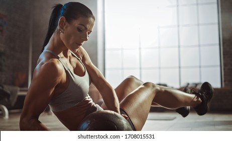 Close Up Of A Strong And Fit Athletic Woman In Sport Top Doing Core And Ab Exercises With Ball In A Loft Style Industrial Gym With Motivational Posters. It's Part Of Her Cross Fitness Training Workout