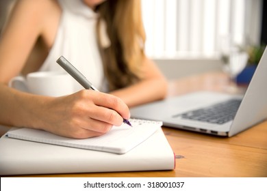 Close up of student business woman hand laptop computer taking notes studying at home