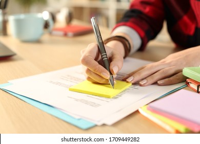Close up of student girl hand writing on post note sitting on a desk at home
