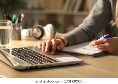 Close Up Of Student Girl Hands Comparing Notes On Laptop Sitting On A Desk At Home At Night