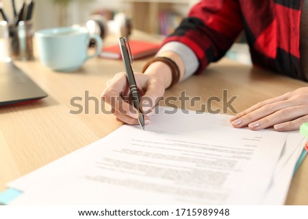 Close up of student girl hands signing contract sitting on a desk at home