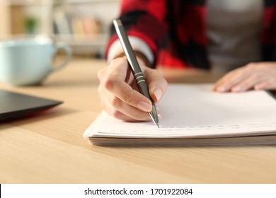 Close up of student girl hands writing notes on notebook at home sitting on a desk 