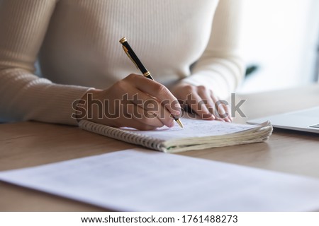 Close up student girl sit at desk holding pen makes notes on exercise book, do task prepare for college exams, female entrepreneur write down important data information creative start up ideas concept
