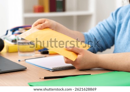 Close up of student hands opens package delivery sitting on a desk at home