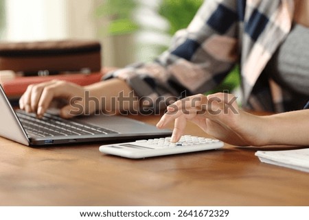 Close up of student hands using laptop and scientific calculator at home