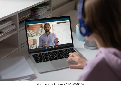 Close up student schoolgirl watching webinar, homeschooling concept, teenage girl wearing headphones using laptop, studying at home, making video call, African American teacher explaining - Powered by Shutterstock