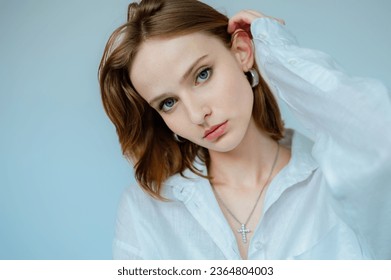 Close up studio beauty portrait of young beautiful woman with healthy flawless radiant freckled skin posing on light blue background. Natural day light.  Copy, empty space for text - Shutterstock ID 2364804003