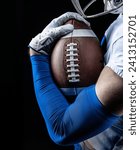 Close up studio photo of an American Football player holding tightly onto a football. Good generic American Football photo