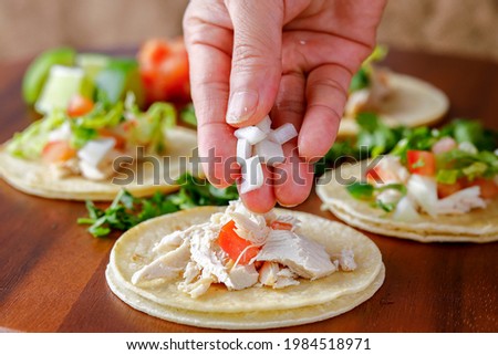 A close up studio photo of putting chopped onions on a street taco.