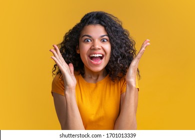 Close up studio portrait of beautiful dark skinned girl with amazed face expression on bright colored yellow background. Cute girl celebration victory in online lottery, she hit the jackpot. - Shutterstock ID 1701013339