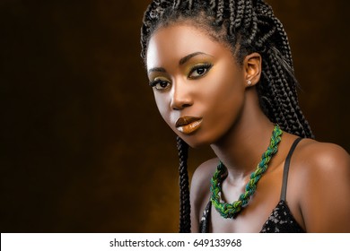 Close up Studio portrait of beautiful young african woman with braids. Low key face shot of elegant girl looking at camera against dark background.