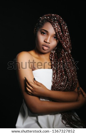 Close up Studio portrait of beautiful young African woman with braids. Low key face shot of elegant girl dark background. 