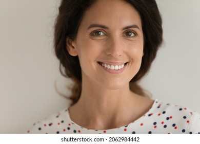 Close up studio portrait of happy beautiful Latin 30s woman with fine face skin looking at camera with toothy smile. Young mid adult female model isolated on white. Dental care, cosmetology concept
