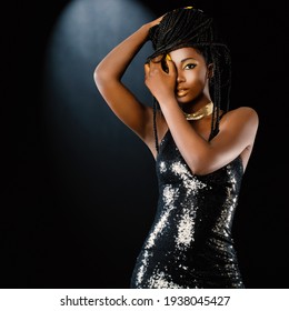Nahaufnahme eines Studioporträts junger attraktiver afrikanischer Frauen, die ein Partykleid auf dunklem Hintergrund tragen. Sexy Mädchen, das mit Braiden spielt. 