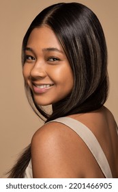 close up studio portrait of young and beautiful African American woman in her 20s with perfect skin smiling looking over her shoulder and posing on neutral background Stock Photo
