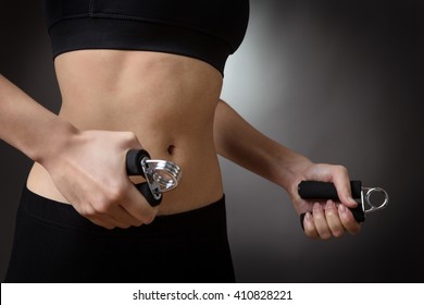 Close up studio shot of a fitness womans abdomen.  using hand grip exercise for strength. 