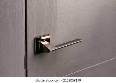 Close up of stylish new metal door knob on modern interior door. Shiny silver door handle on light gray door. Concept of interior details. - Powered by Shutterstock