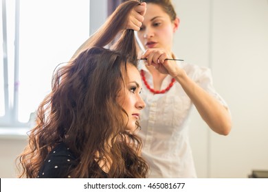 Close up of stylist's hand using curling iron for hair curls.