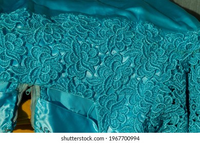 Close Up Of Suare Neckline Of A Cocktail Dress In Turquoise Satin And Macrame Lace