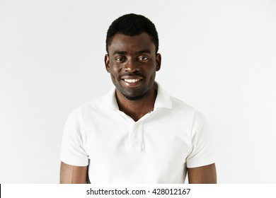 Close Up Of Successful Young Black Entrepreneur Wearing White Polo Shirt Looking And Smiling At The Camera With Winning Happy Expression, Achieving Business Goals. Success And Achievement Concept