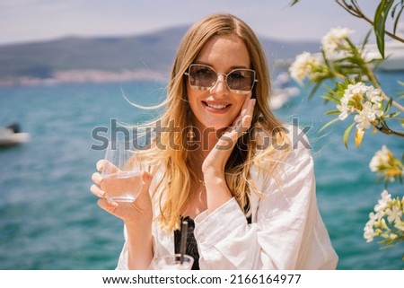 Close up summer portrait of pretty blonde elegant woman posing in the restaraunt near sea, luxury vacation.