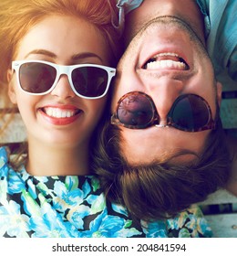 Close up sunny portrait of happy stylish couple smiling and having fun together, wearing stylish sunglasses. Bright sunshine colors.