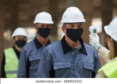 Close Up Of Supervisor Measuring Temperature Of Workers With Contactless Thermometer At Construction Site, Corona Virus Safety