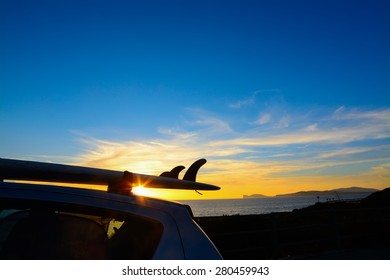 Close Up Of A Surfboard On A Car Roof At Sunset