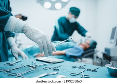 Close up surgeon doctor's hand with hygiene glove taking sterile surgical instrument tool, equipment in operating room patient in background for surgery. Hospital, medical healthcare emergency concept - Powered by Shutterstock