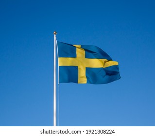 Close up of the Swedish flag flattering in the wind with clear blue sky in the background. Selected focus.
