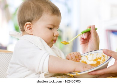 Close Up Of Sweet Messy Baby Boy Playing With Food In The Bowl While Eating.