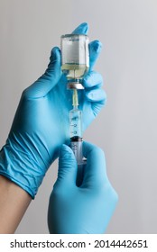 Close up of syringe in doctor or nurse's hand drawing up covid-19 vaccine from a vial to vaccinate into patients for immunization and prevention from coronavirus pandemic.  Flu, vaccination concept - Shutterstock ID 2014442651