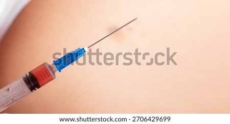 Close up of a syringe with needle and clear solution against human skin, suitable for healthcare and vaccination concepts.