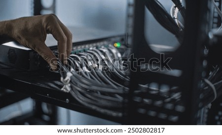 Close up of system administrator connecting cables with server rack, working in server room. Maintenance of LAN or web servers. Operation of information systems and networks. Data storage center.