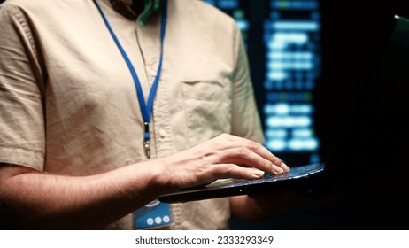 Close up of system administrator using laptop to check operational server clusters. Rackmounts in computer network security data center providing processing and memory resources for several workloads